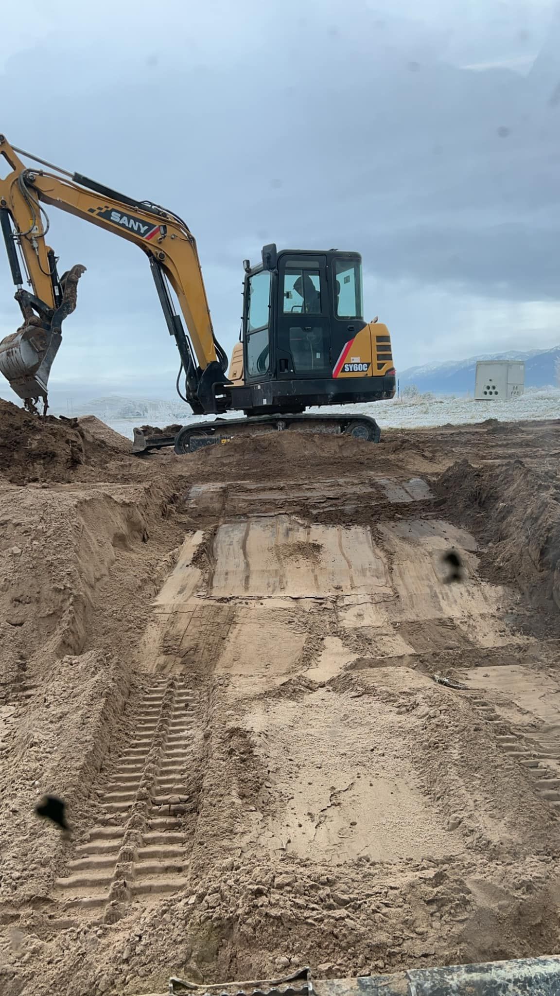An excavator is digging a hole in the dirt on a construction site.