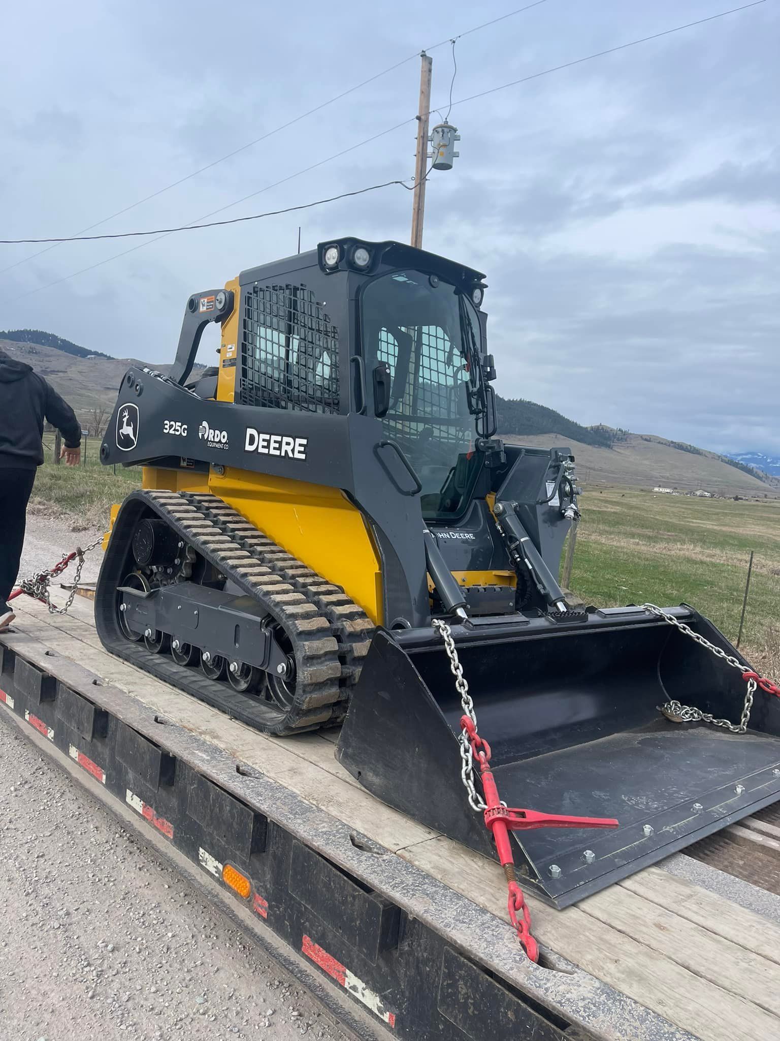A yellow and black tractor is sitting on top of a trailer.