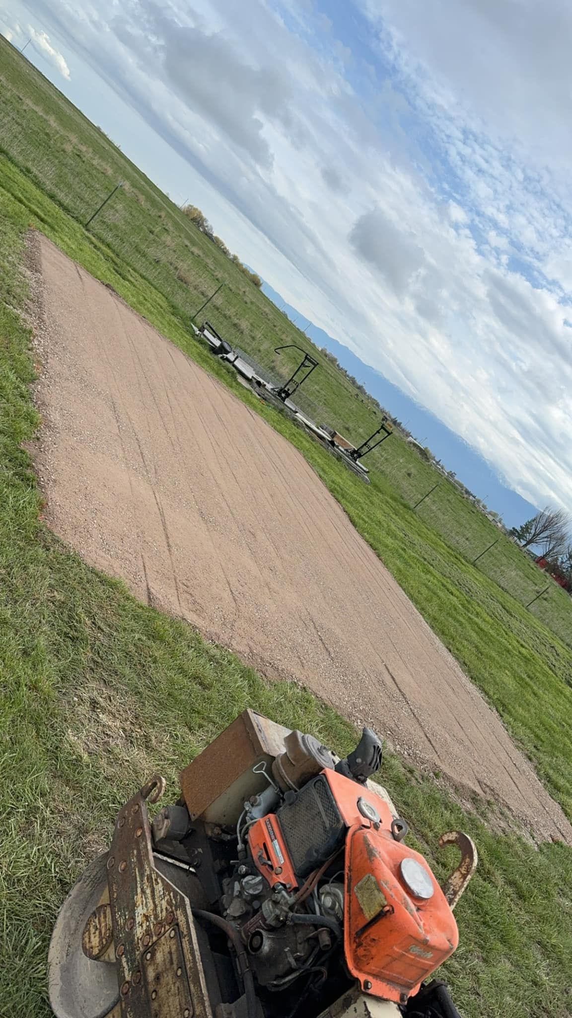 A motorcycle is parked on the side of a dirt road in a field.