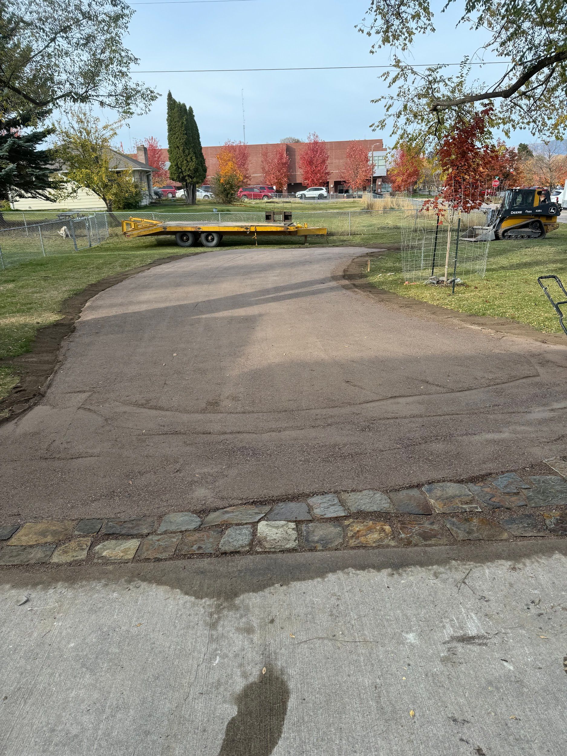 A dirt road going through a park with a large building in the background.