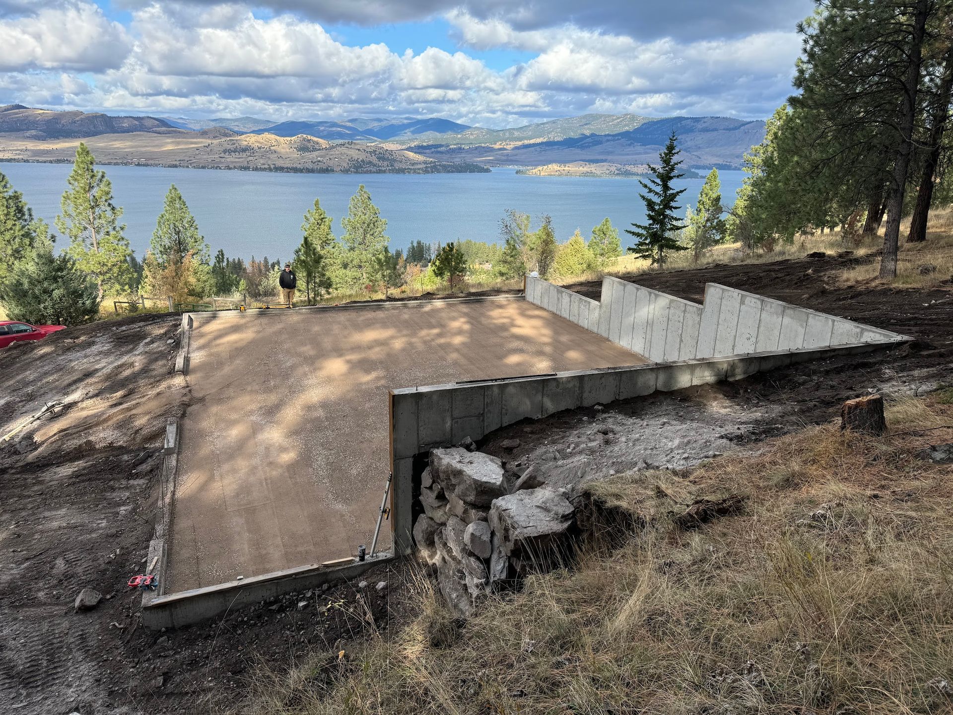 A concrete foundation is being built on a hill overlooking a lake.