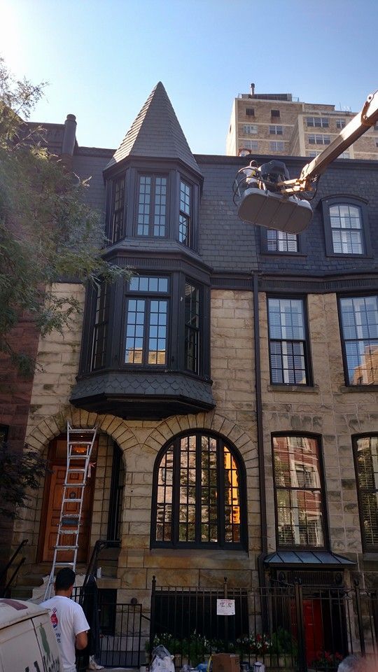 A Man Is Standing In Front Of A Large Building With A Ladder — Chicago, IL — McMaster Painting