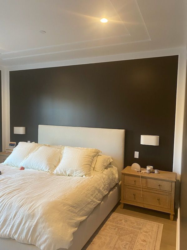 A bedroom with a bed , nightstand , and black walls.