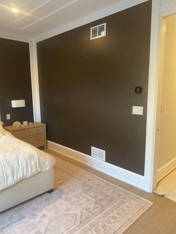 A bedroom with a bed , nightstand , rug and brown walls.