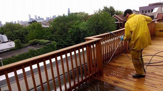 Man in a Yellow Raincoat is Cleaning a Wooden Deck — Chicago, IL — McMaster Painting