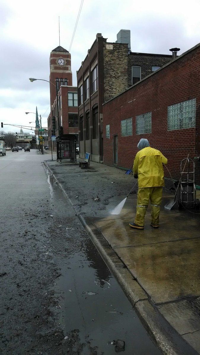 A Man In A Yellow Raincoat Is Cleaning A Sidewalk — Chicago, IL — McMaster Painting