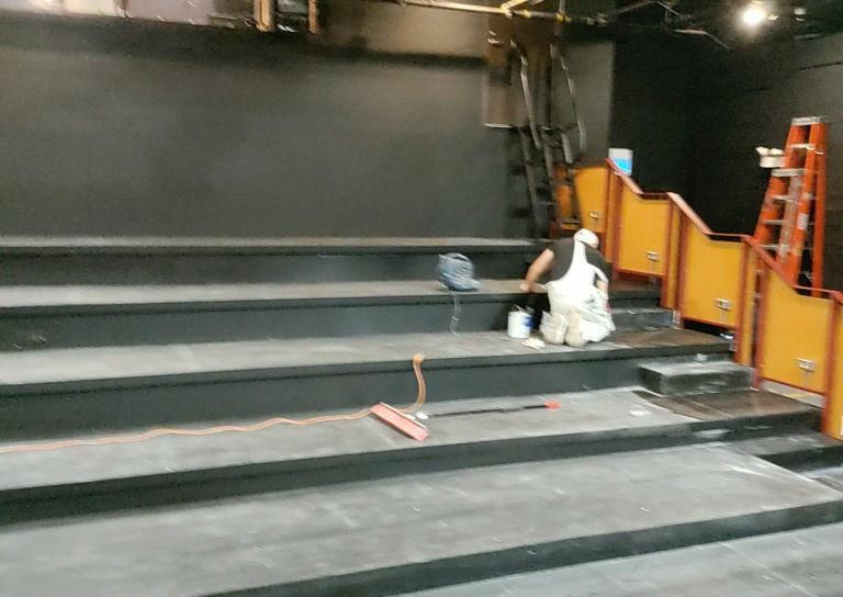 A Man Is Kneeling and Painting on The Steps of An Auditorium - Chicago, IL - McMaster Painting