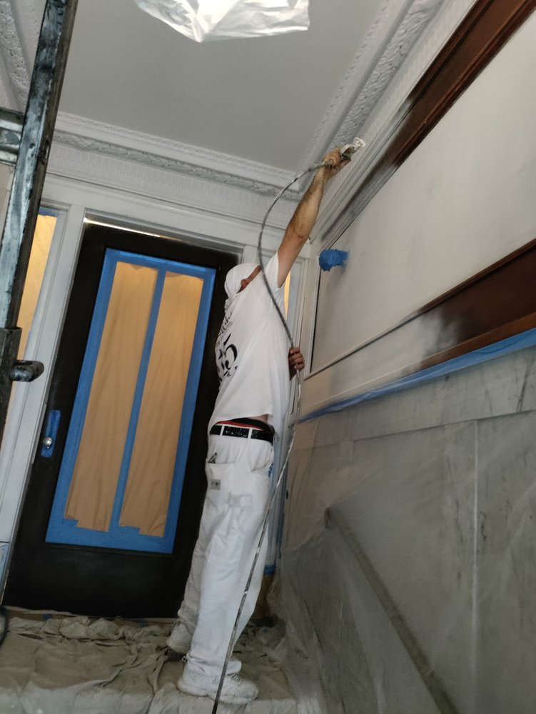 A Man Is Painting A Wall With A Sprayer — Chicago, IL — McMaster Painting