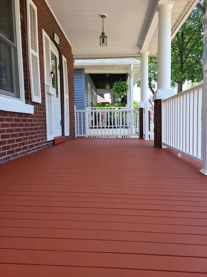 A porch with a red wooden floor and white railing on a brick house — Chicago, IL — McMaster Painting	
