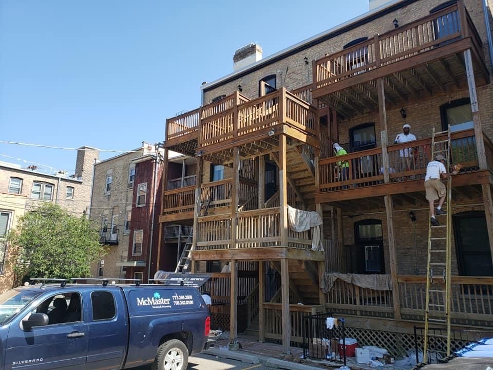 A blue truck is parked in front of a building under construction — Chicago, IL — McMaster Painting	
