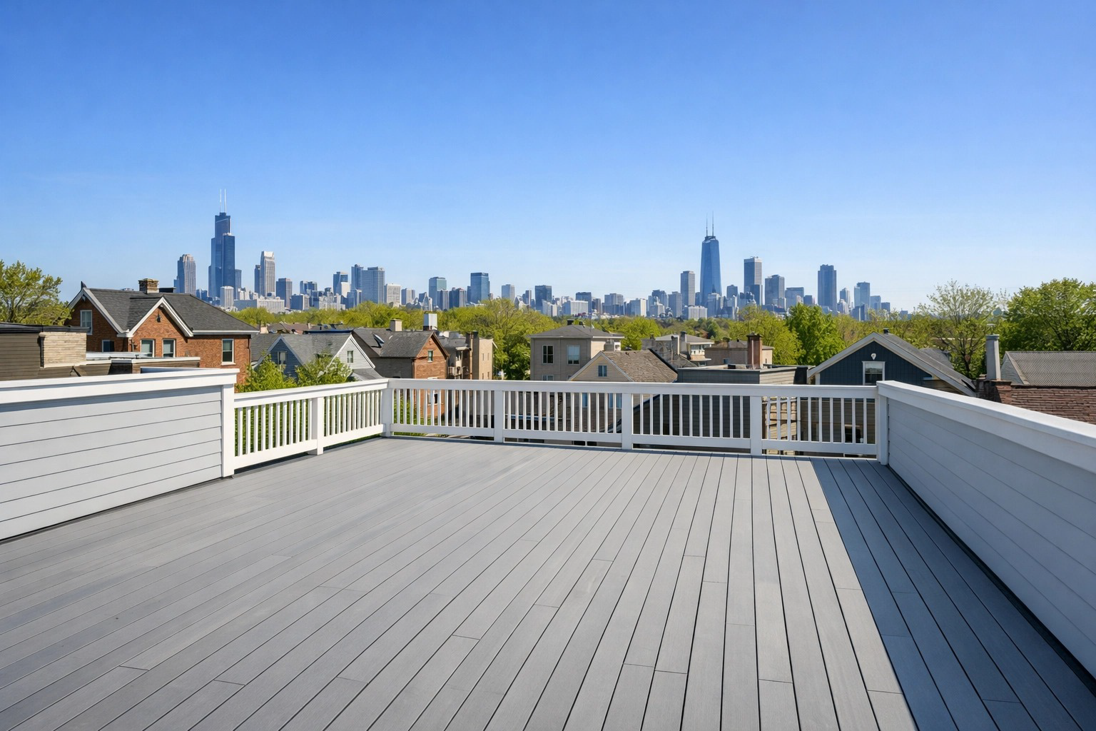 A rooftop deck featuring grey composite decking and white railings, overlooking the Chicago skyline on a clear day. A rooftop deck featuring grey composite decking and white railings, overlooking the Chicago skyline on a clear day.