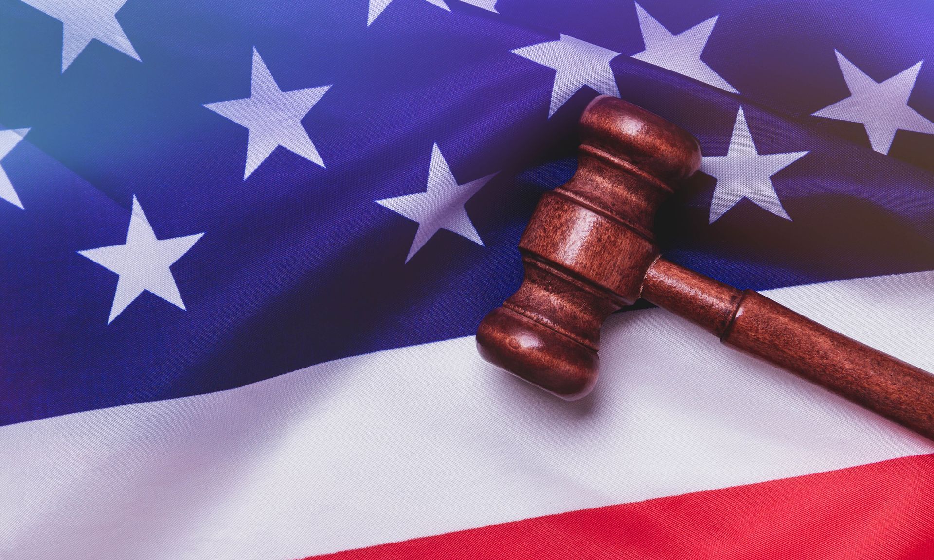 A wooden gavel is sitting on top of an american flag. A wooden gavel is sitting on top of an american flag.