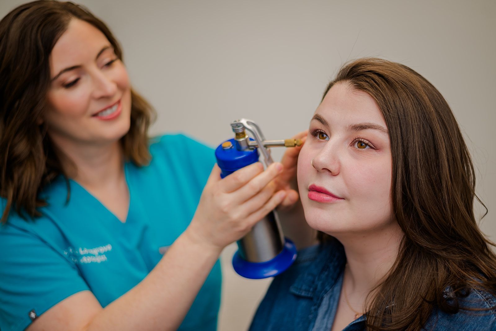 Woman receiving cryotherapy near her ear from a medical professional in a clinic setting. Dr. Lovegrove and patient.