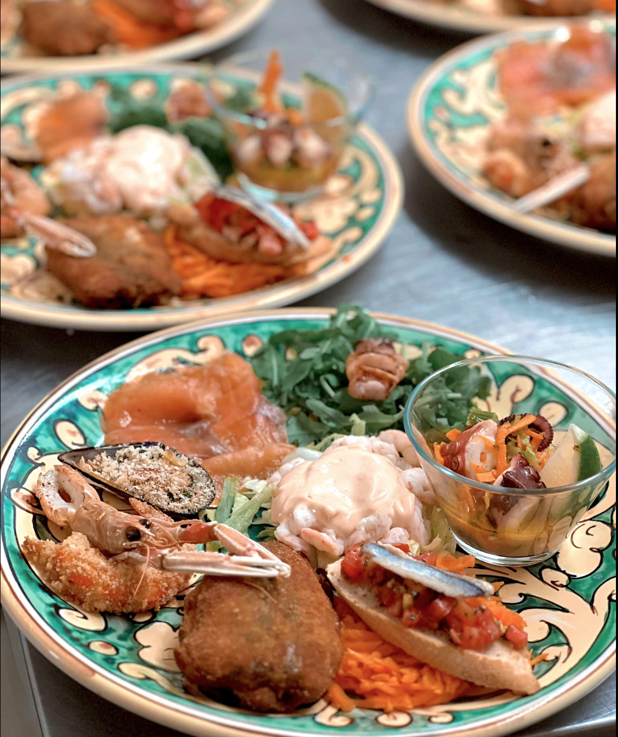 Un piatto di cibo è appoggiato su un tavolo insieme ad altri piatti di cibo.