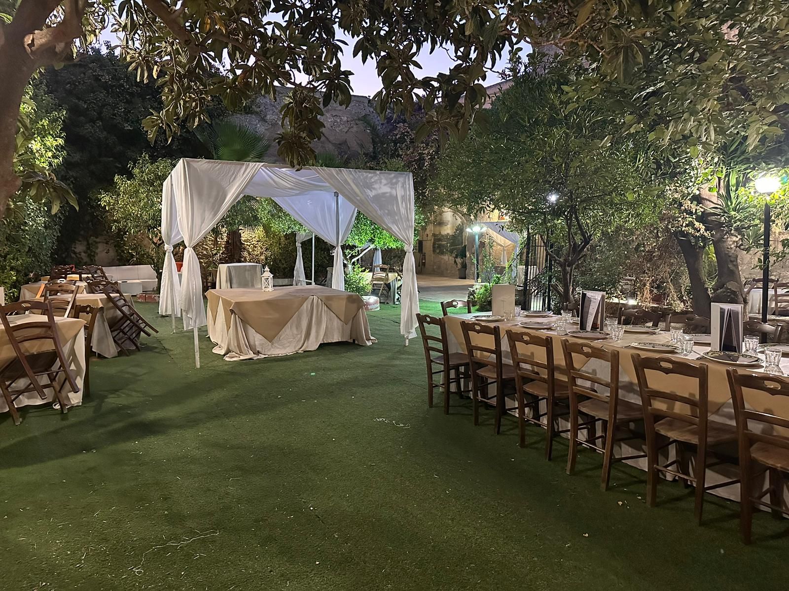 Un prato con tavoli e sedie allestiti per un ricevimento di nozze.