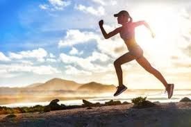 Woman running, silhouetted against a sunny sky and coastal landscape.
