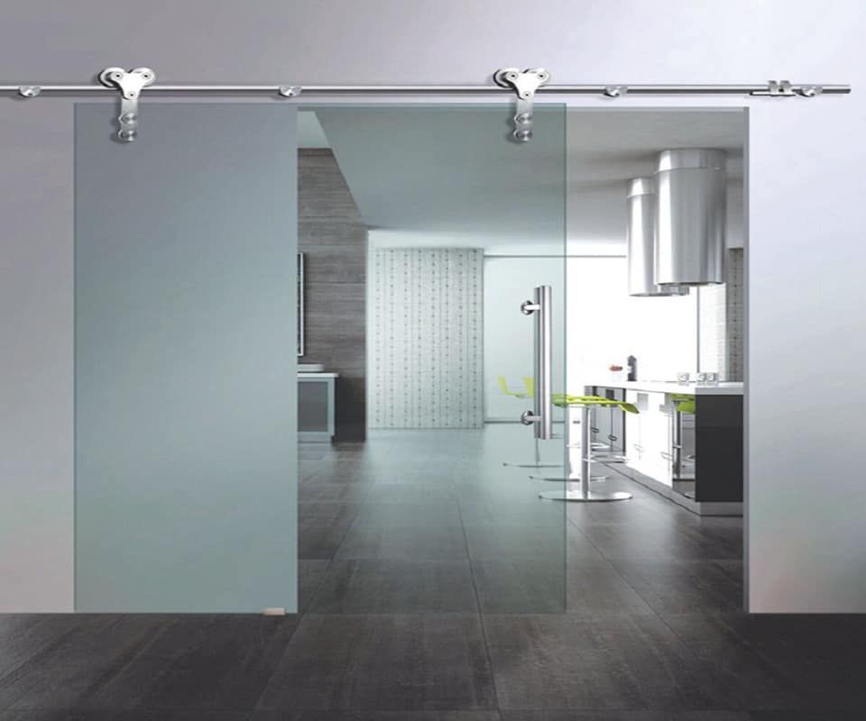 Porta scorrevole in vetro, ferramenta montata a parete. Vista interna di una casa moderna con cucina e soggiorno.