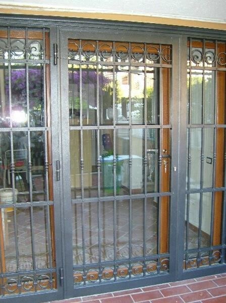 Porta esterna in vetro con barre di sicurezza in metallo nero e finiture marroni.