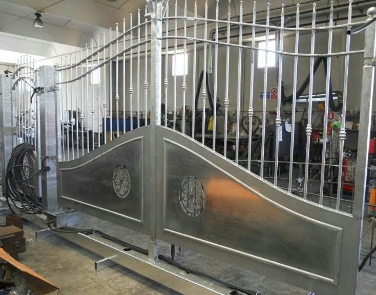 Cancello in acciaio inox con elementi decorativi, in un ambiente da officina.