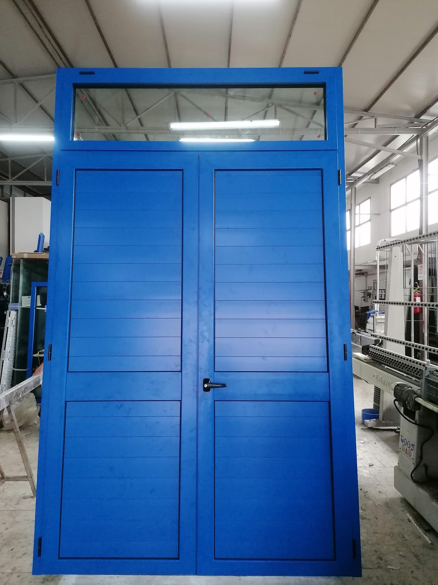 Doppie porte blu con linee orizzontali e una finestra a traversa in alto.