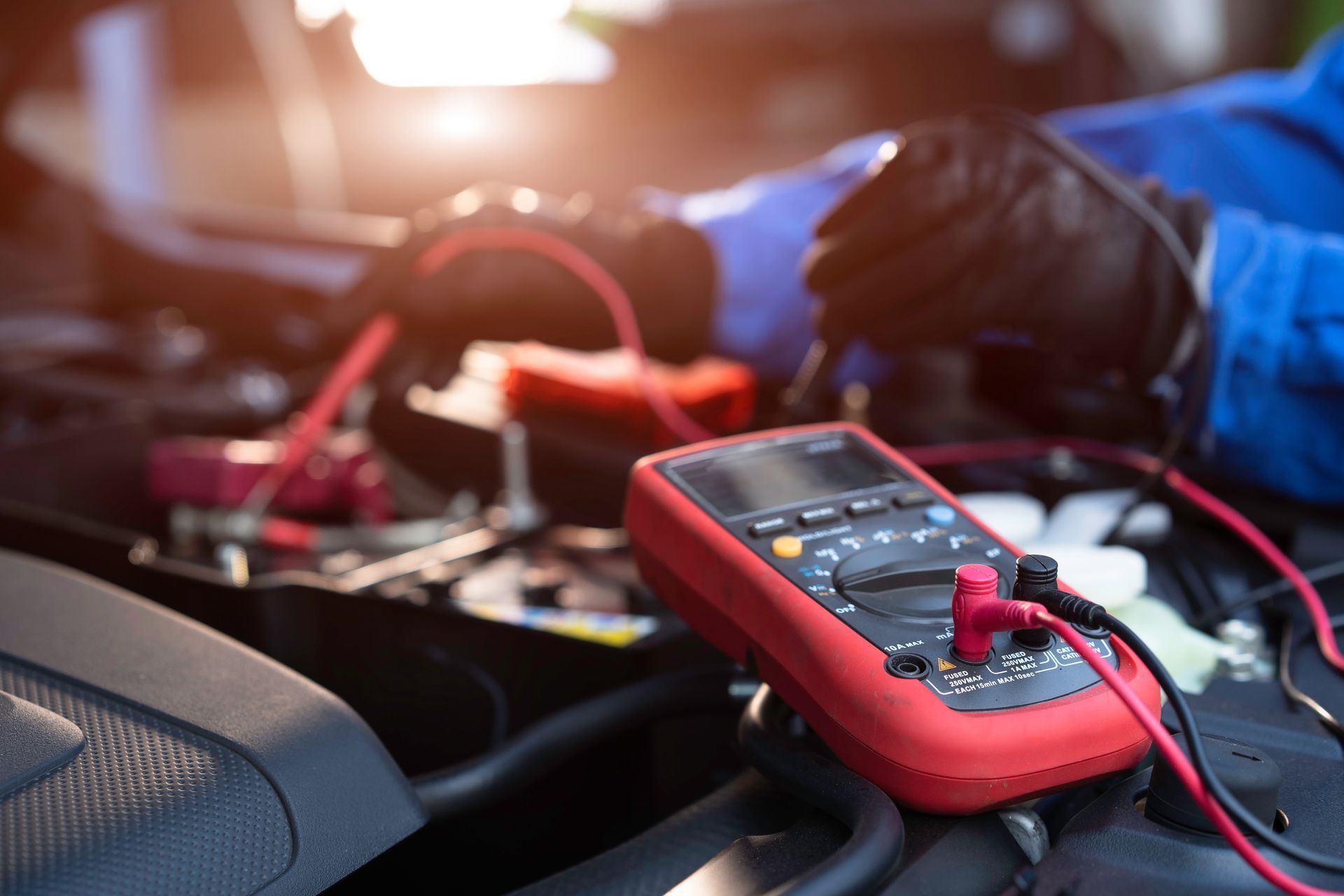 A close-up of a red digital multimeter with probes connected during diagnostic testing.