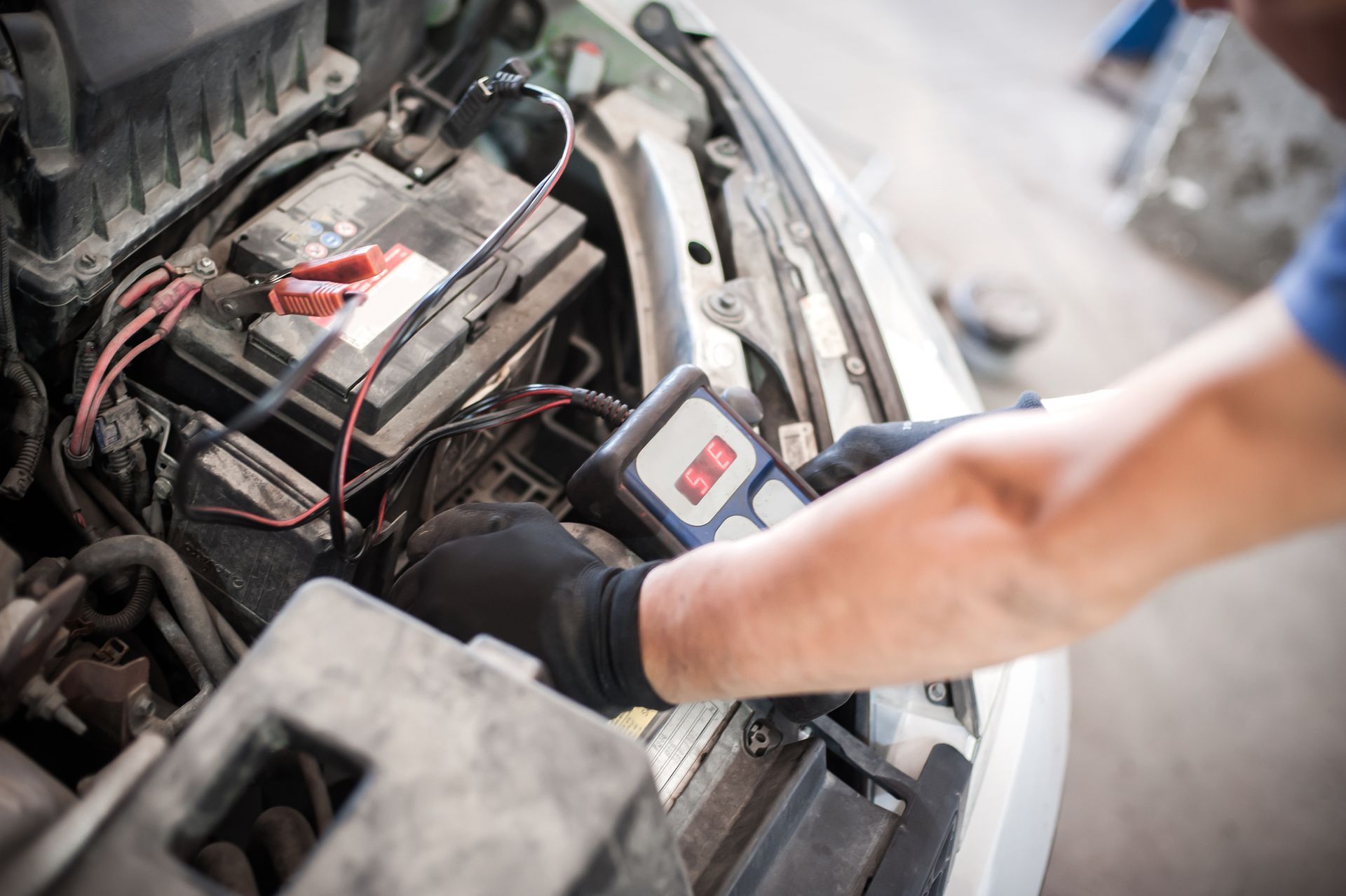 Car technician checking battery, highlighting automotive battery service for vehicle care.