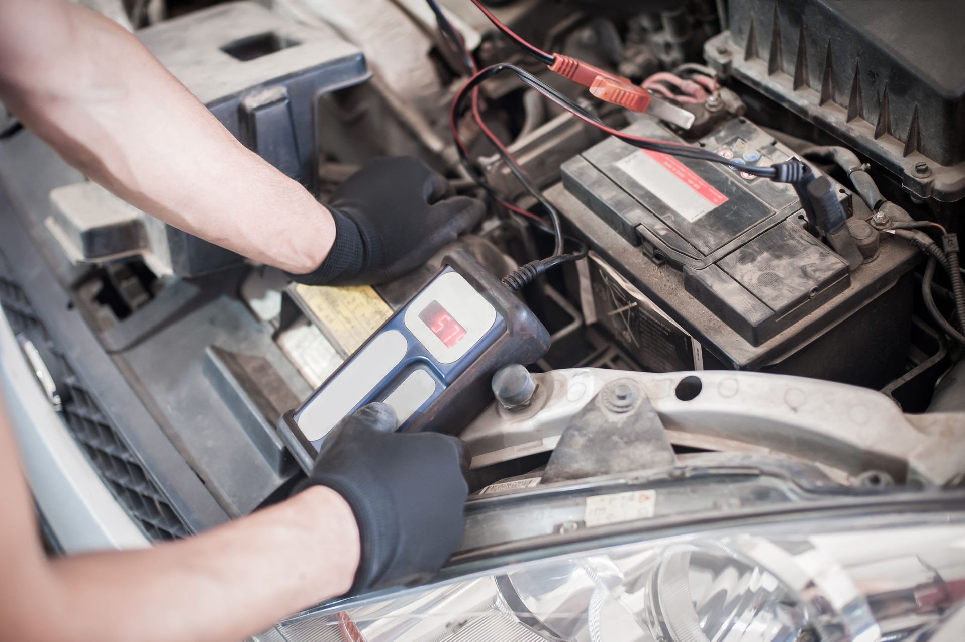 Car mechanic inspecting car battery, showcasing automotive battery service for reliability.