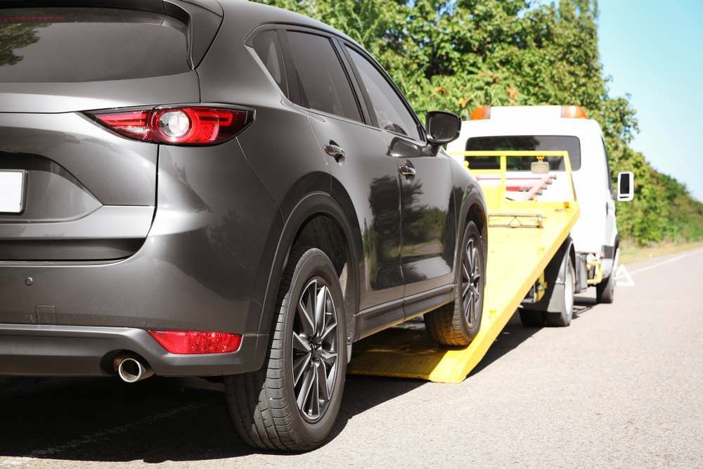Towing The Black Car With Yellow Flatbed Tow Truck — Big Tim's Towing in Belmont, NSW