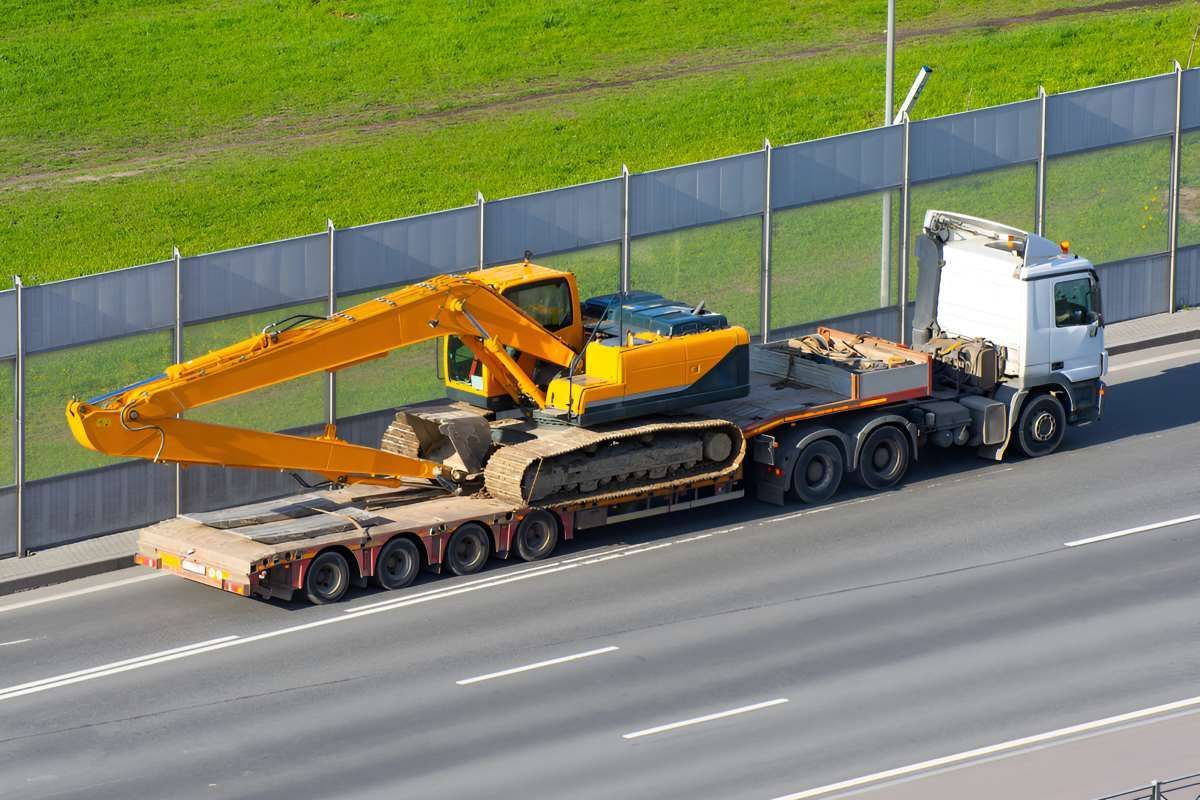 An Excavator Is Being Moved By Trailer On The Highway — Big Tim's Towing in Maryland, NSW