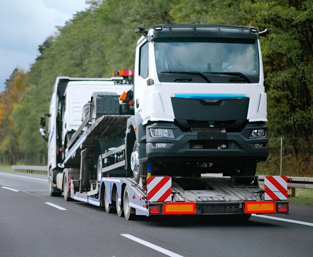A Tow Truck Is Driving Down A Highway With A Car On The Back Of It — Big Tim's Towing in Wickham, NSW