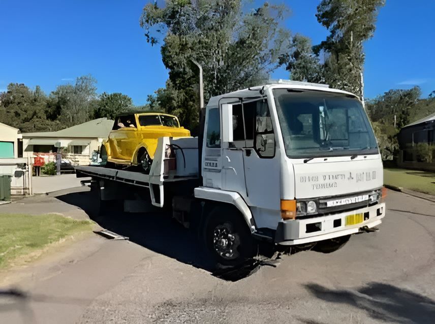 Small Yellow Car Is Loading Into The Tow Truck — Big Tim's Towing in Black Hill, NSW