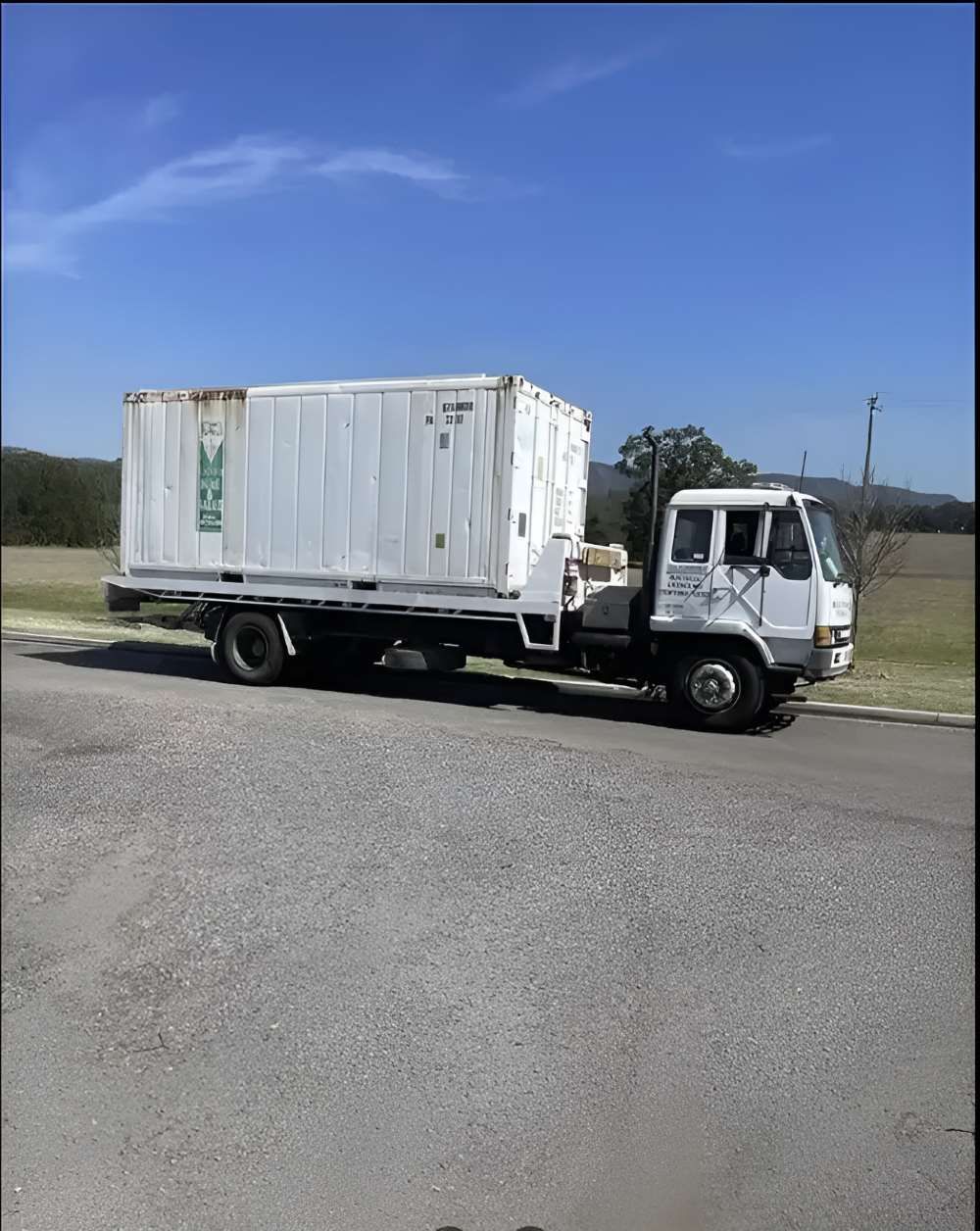 A White Tow Truck Is Moving The White Container — Big Tim's Towing in Merewether, NSW