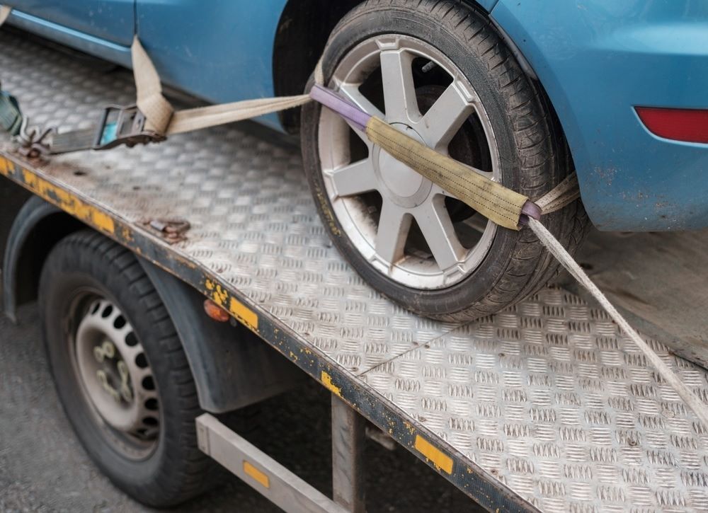 A Tow Truck Is Carrying A Blue Car — Big Tim's Towing in Eleebana, NSW