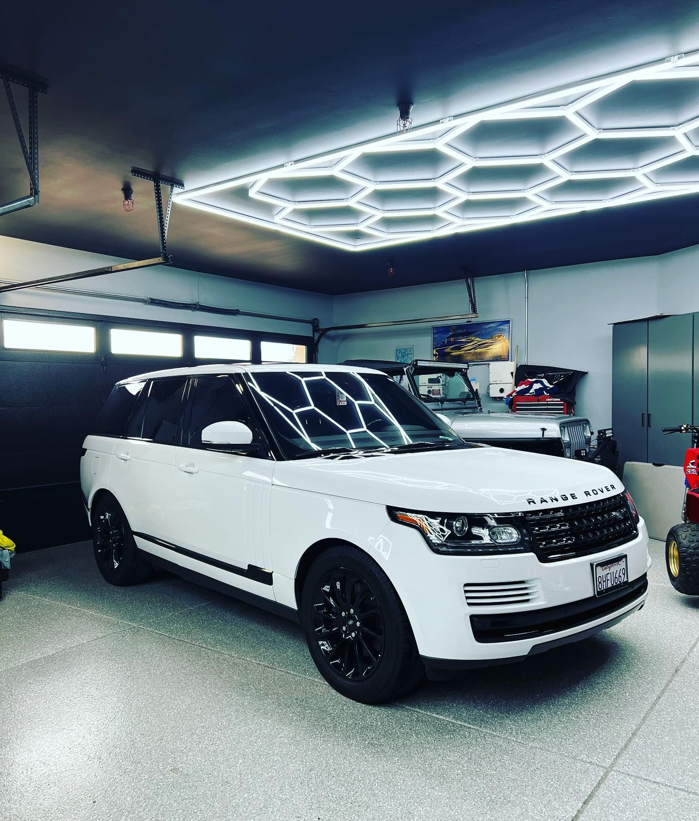 A white range rover is parked in a garage.