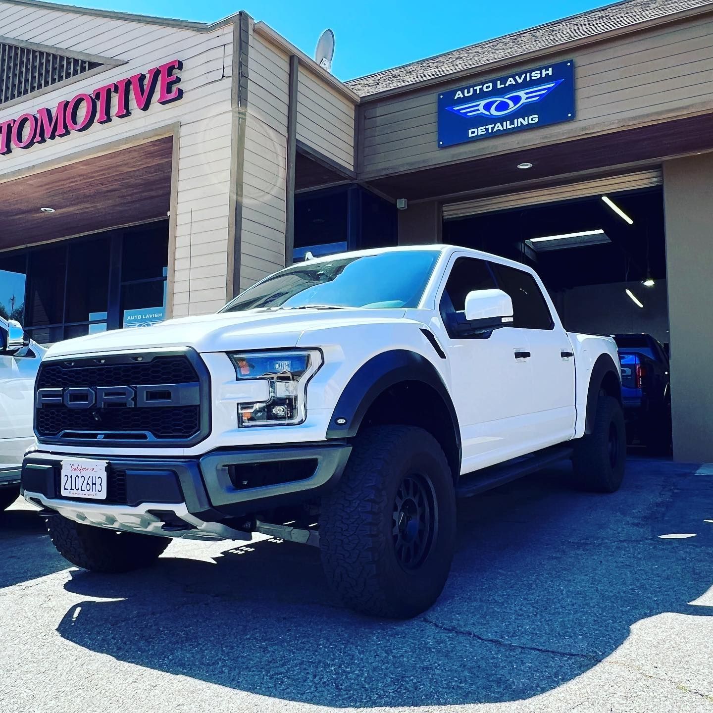 A white truck is parked in front of an automotive store