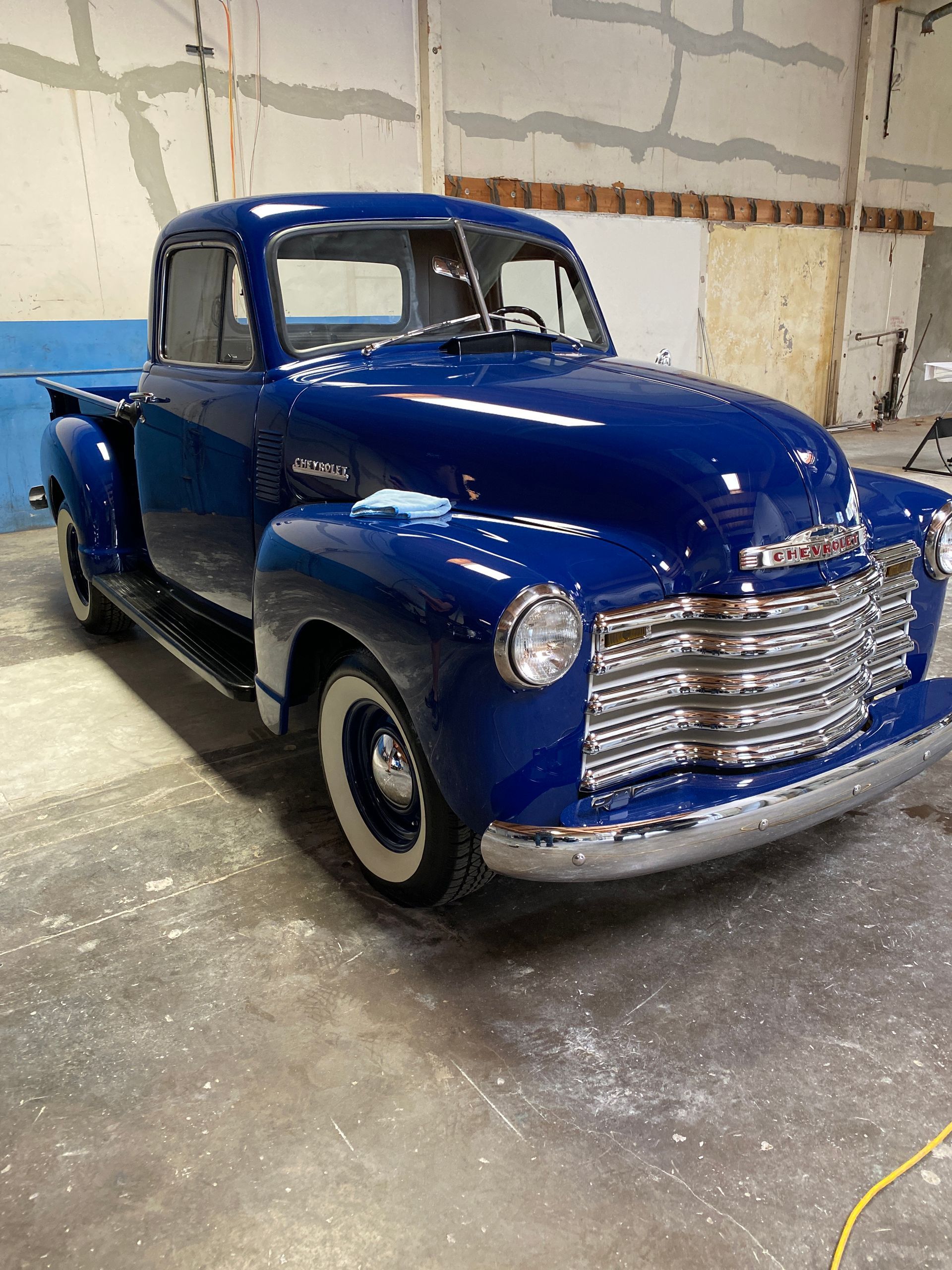 An old blue truck is parked in a garage.