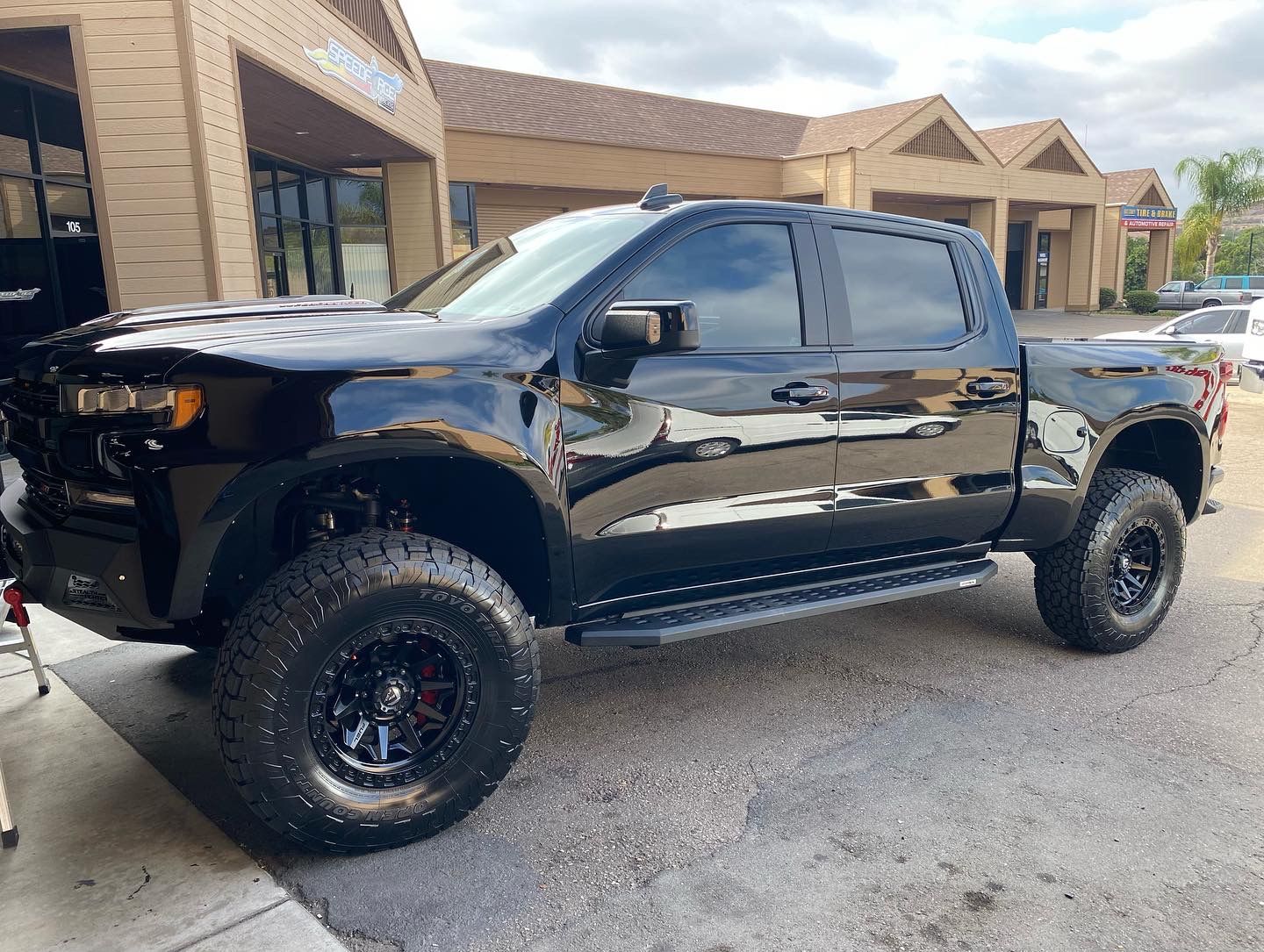 A black truck is parked in front of a building.