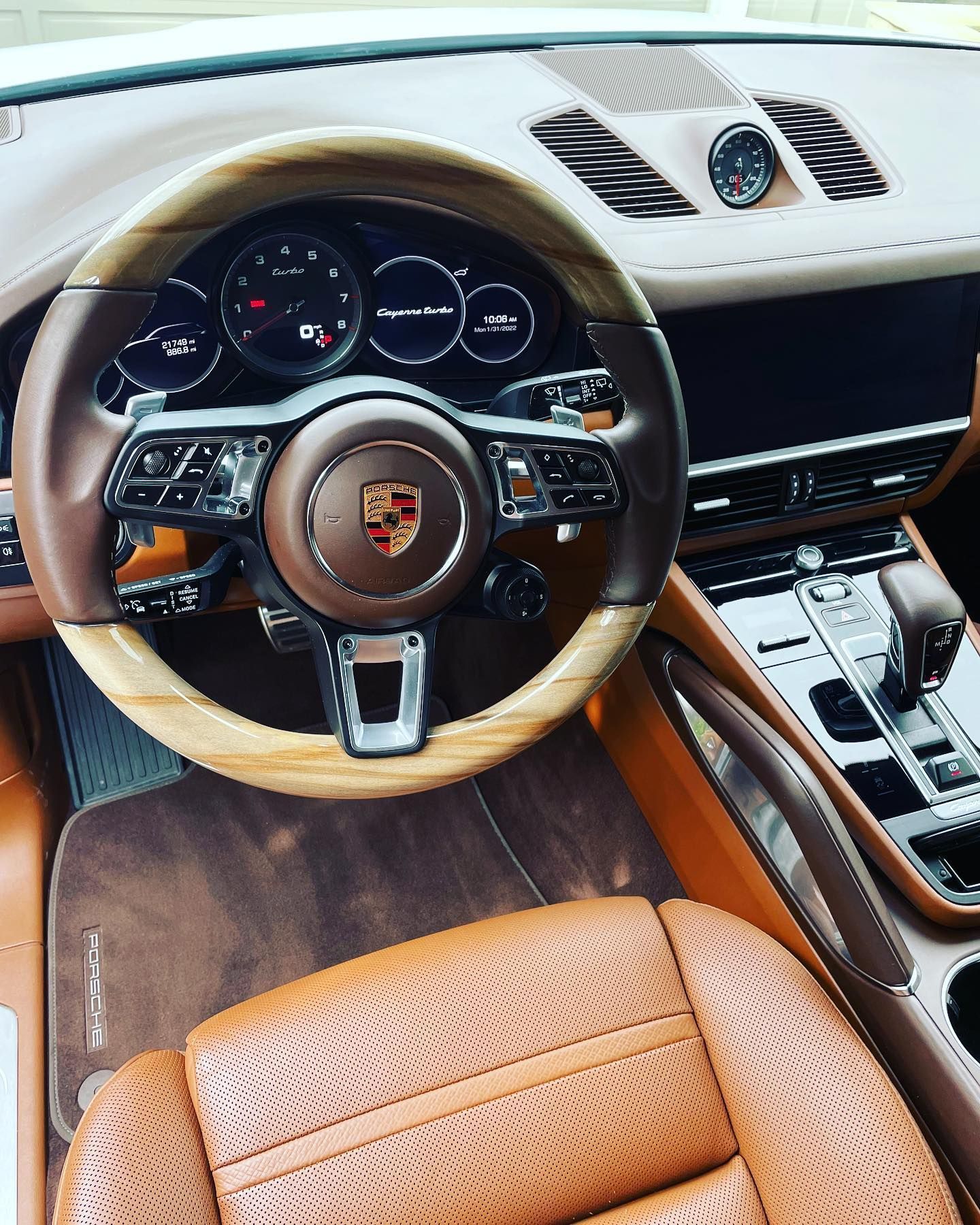The interior of a porsche car with brown leather seats and a wooden steering wheel.