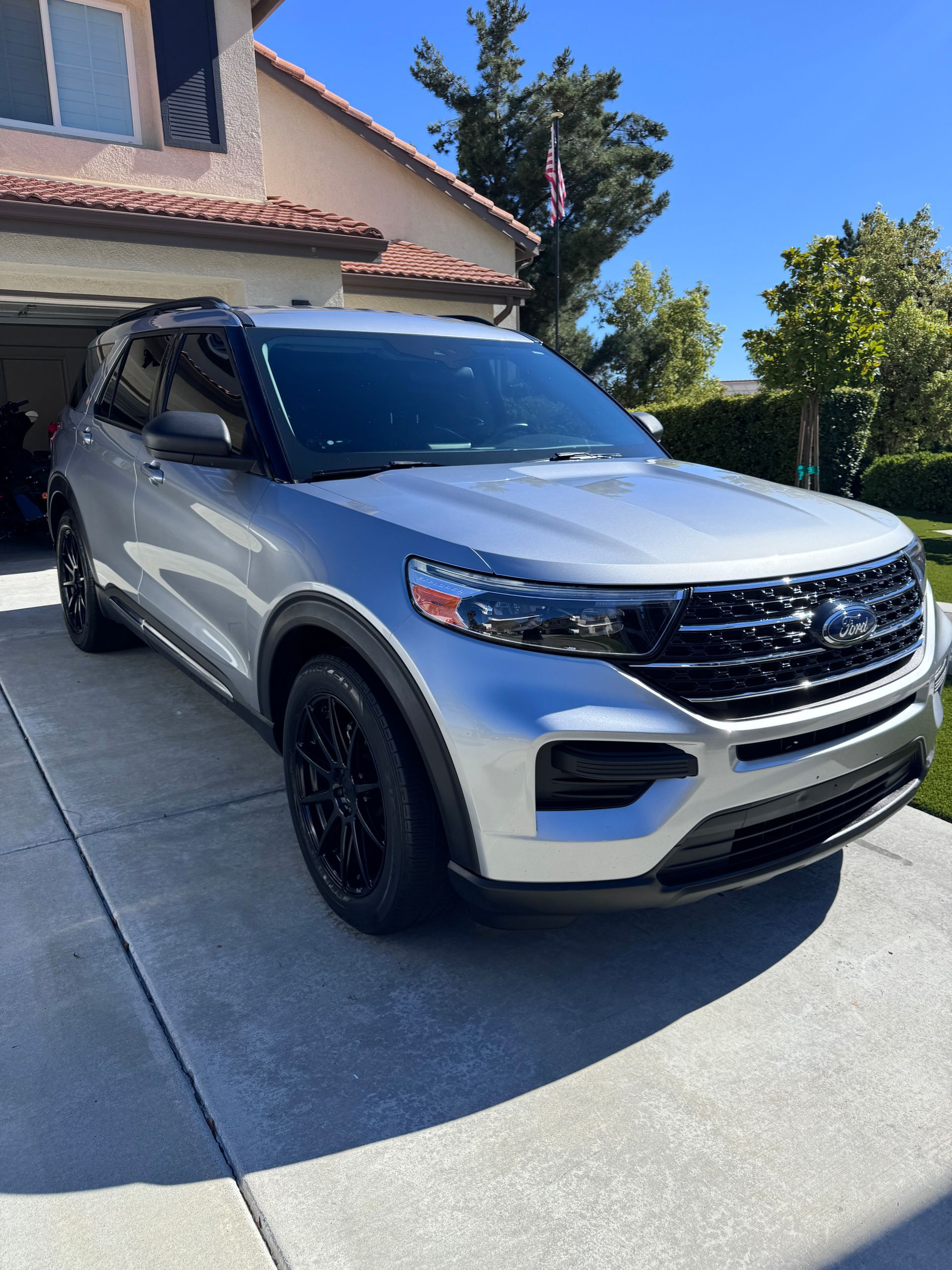 A silver ford explorer is parked in front of a house.