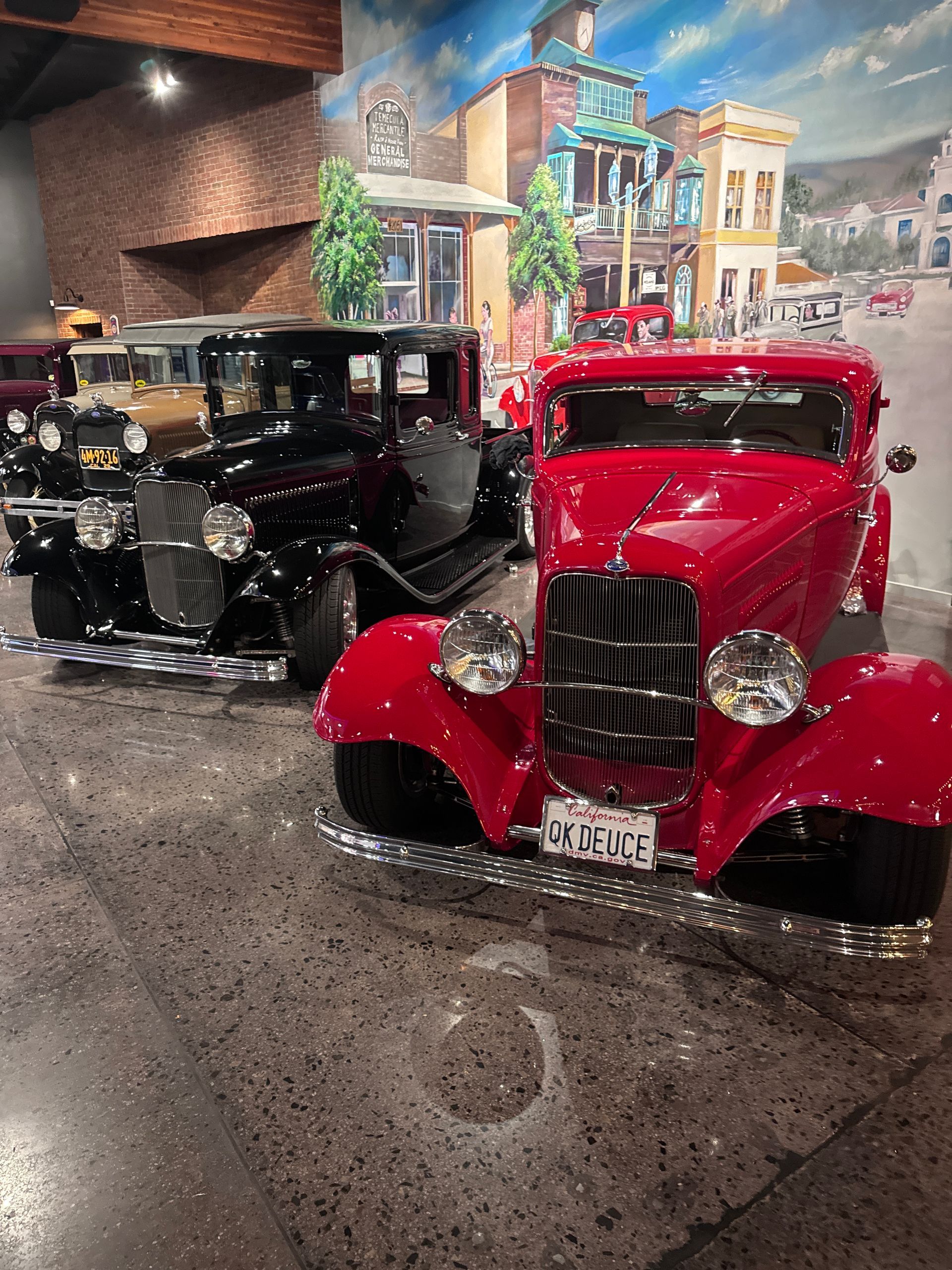 Two old cars are parked next to each other in a museum.