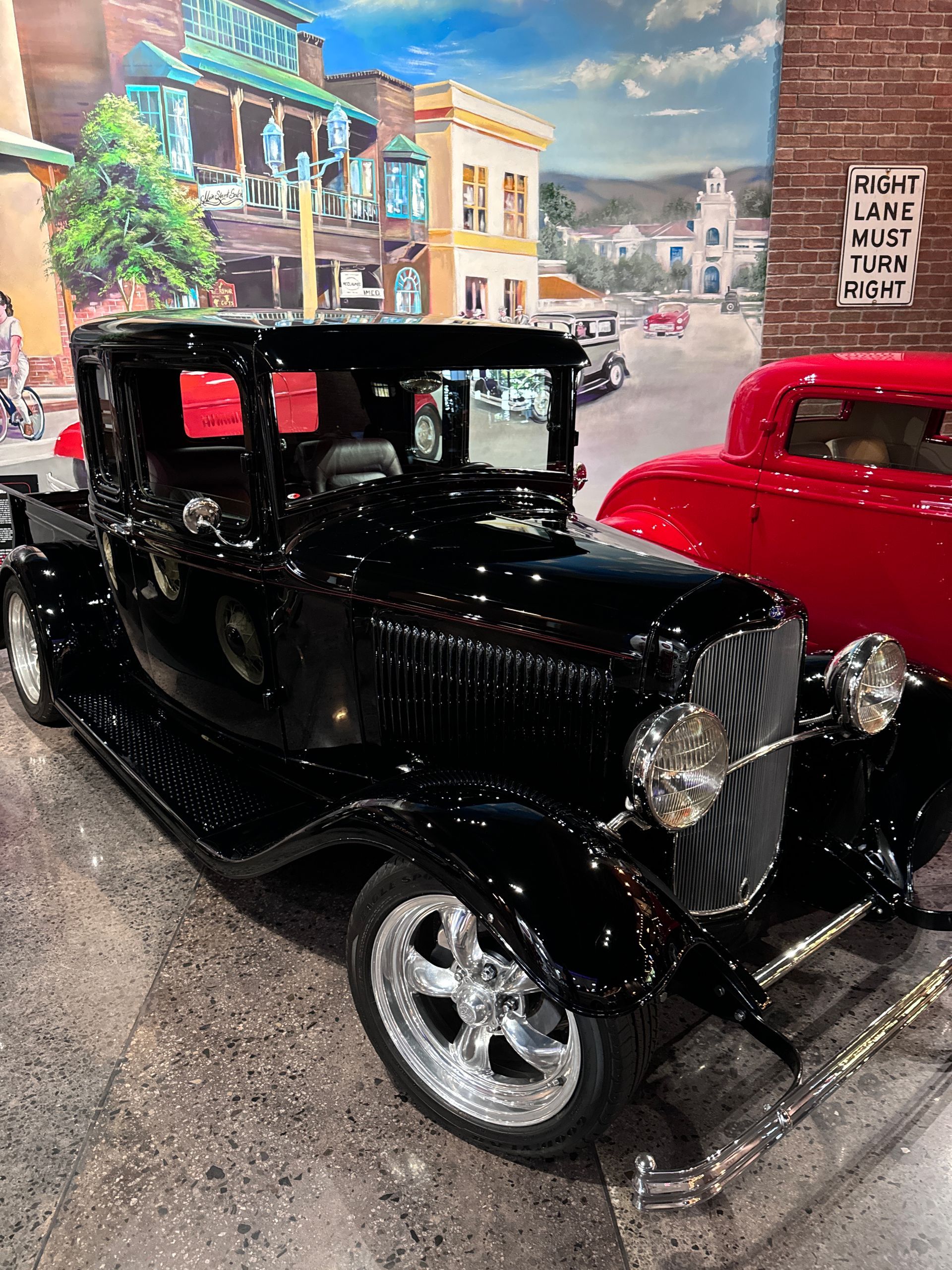 An old black truck is parked in front of a brick building.