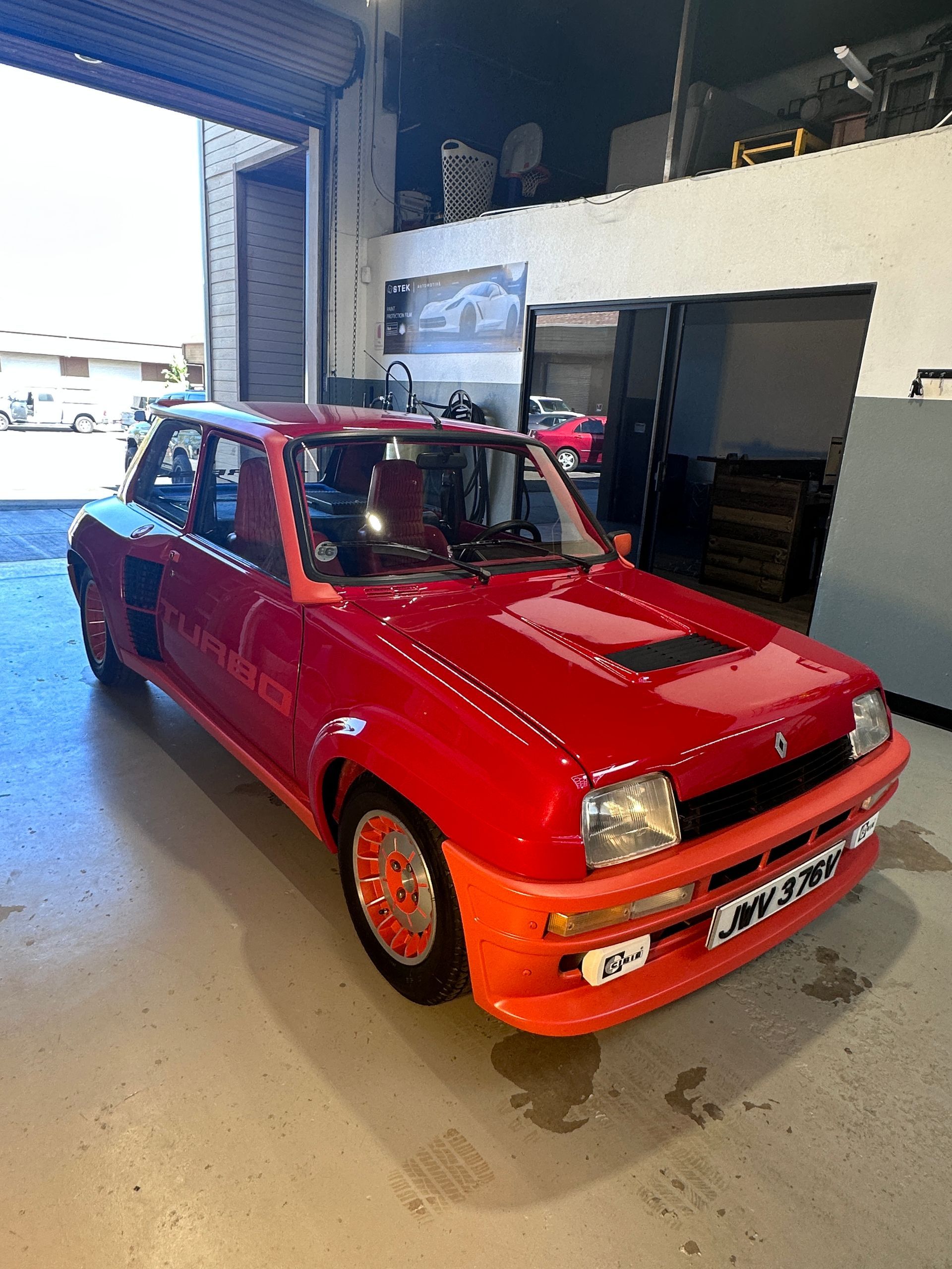 A red and orange car is parked in a garage.