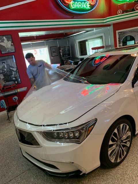 A man is standing next to a white car in a garage