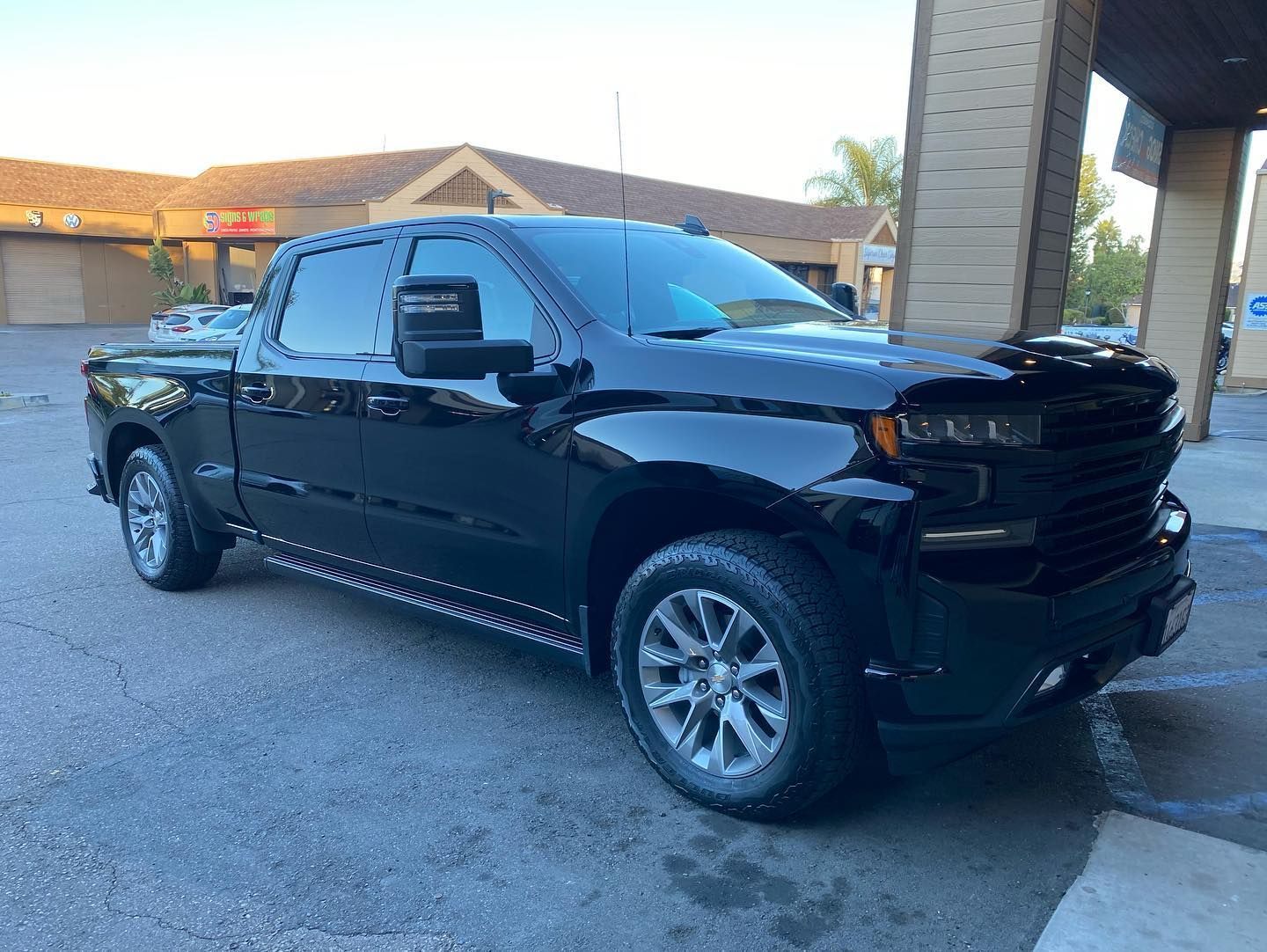 A black truck is parked in front of a building.