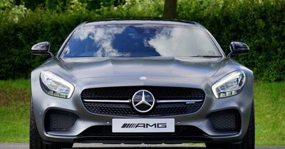 The front of a mercedes amg is parked on the side of the road.