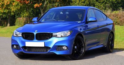 A blue bmw 3 series is parked on the side of the road.