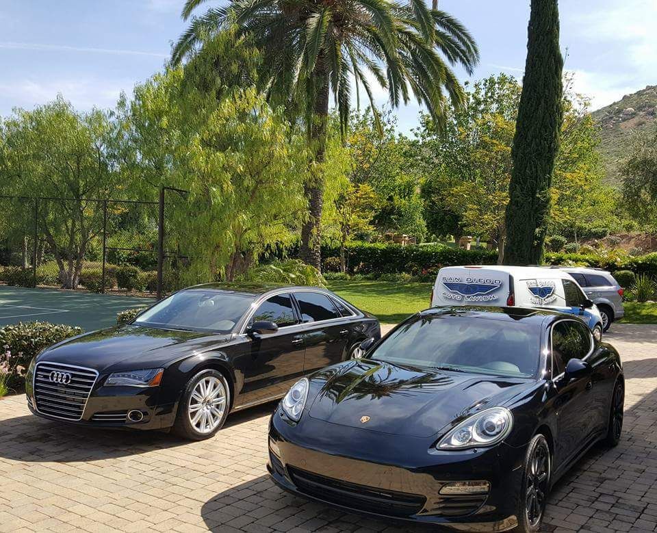 Two black cars are parked next to each other in a driveway.