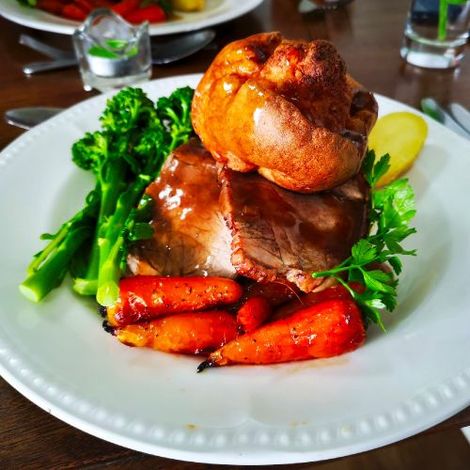 A white plate topped with roast beef carrots and broccoli