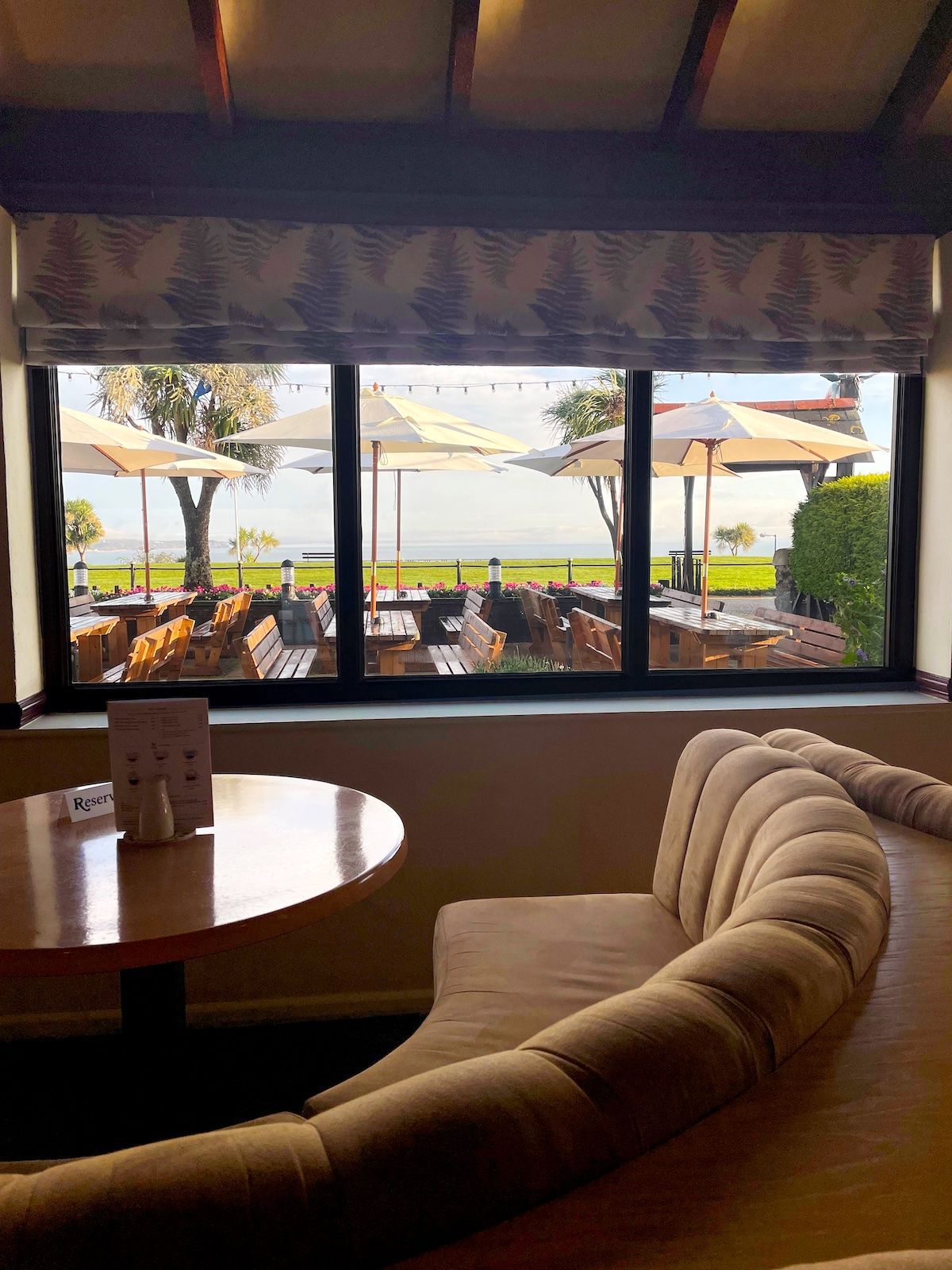 A restaurant with tables and chairs and a large window with a view of the ocean.