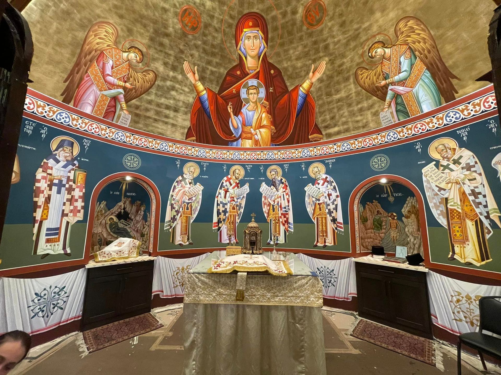 A man is looking at a painting of jesus and mary in a church.